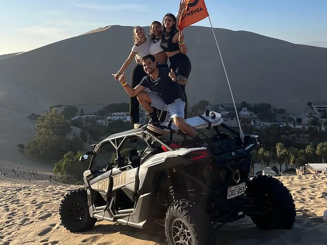 People posing on a dune buggy in the desert.
